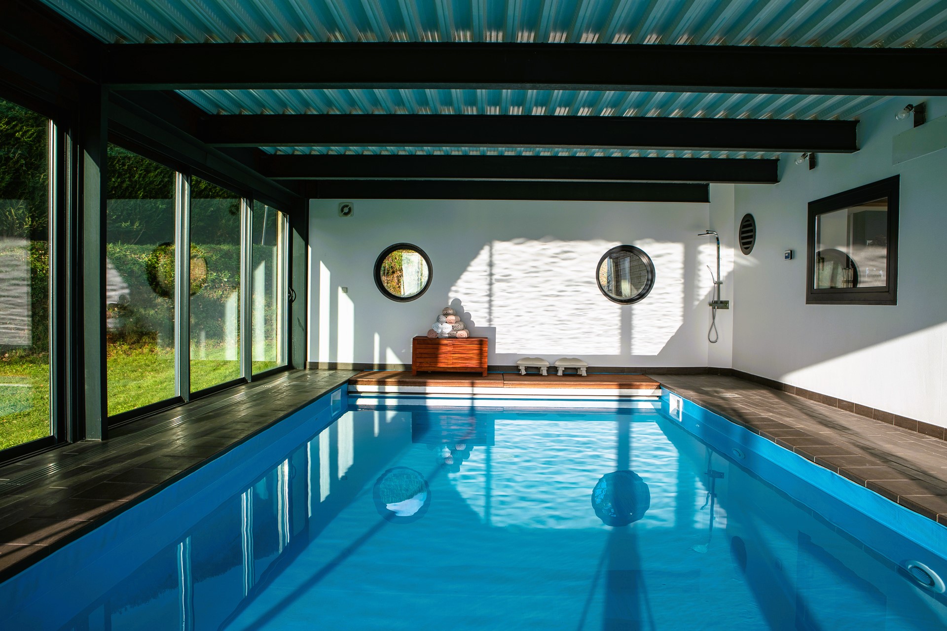 Piscine intérieure couverte de la villa avec baies vitrées sur le jardin