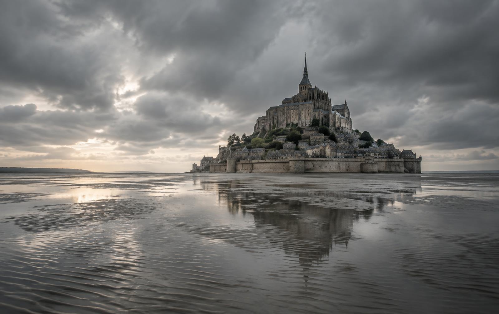 Le Mont Saint-Michel à marée basse sous un ciel gris